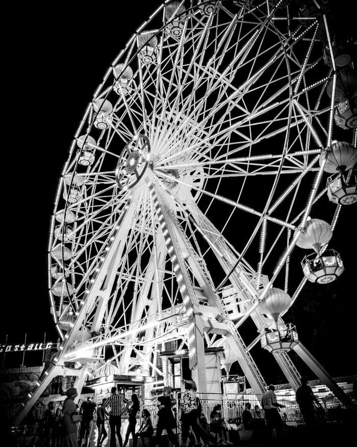Menus Low angle shot of a Ferris wheel illuminated at night in monochrome.
